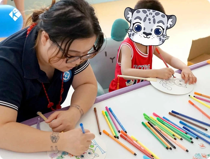 KLIS teachers and kids doing snow‑leopard hand‑fan DIY at Youyou hospital