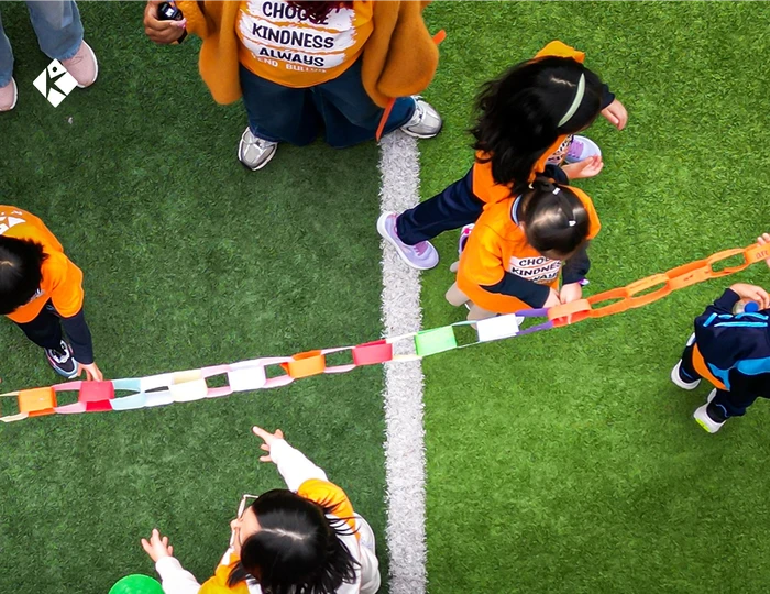 KLIS students linking colorful paper unity chains on the school field during Unity Day anti-bullying activities