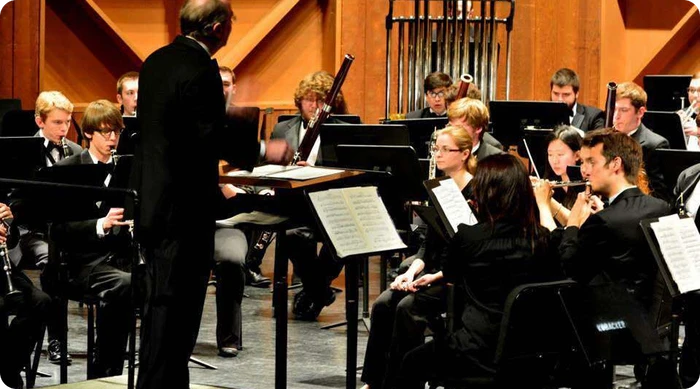 Conductor leading wind ensemble rehearsal with oboe and bassoon sections